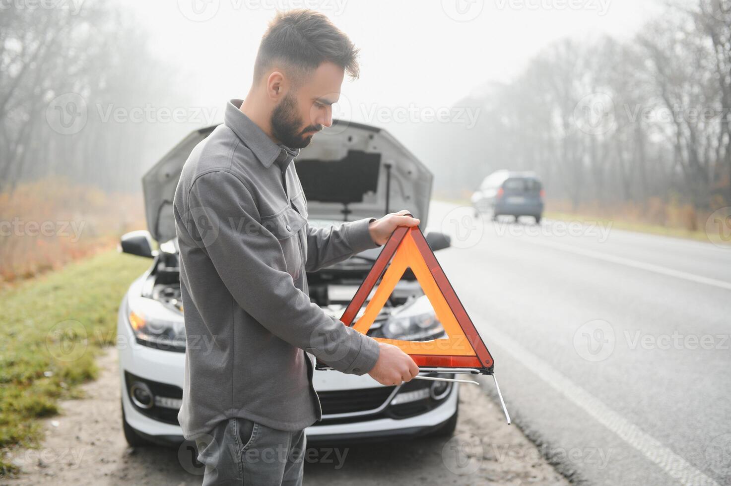 Sad driver having engine problem standing near broken car on the road. Car breakdown concept photo
