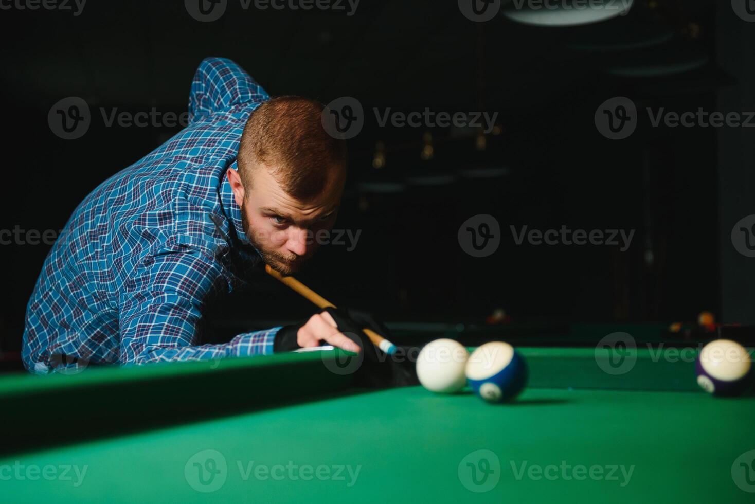 Young handsome man leaning over the table while playing snooker photo