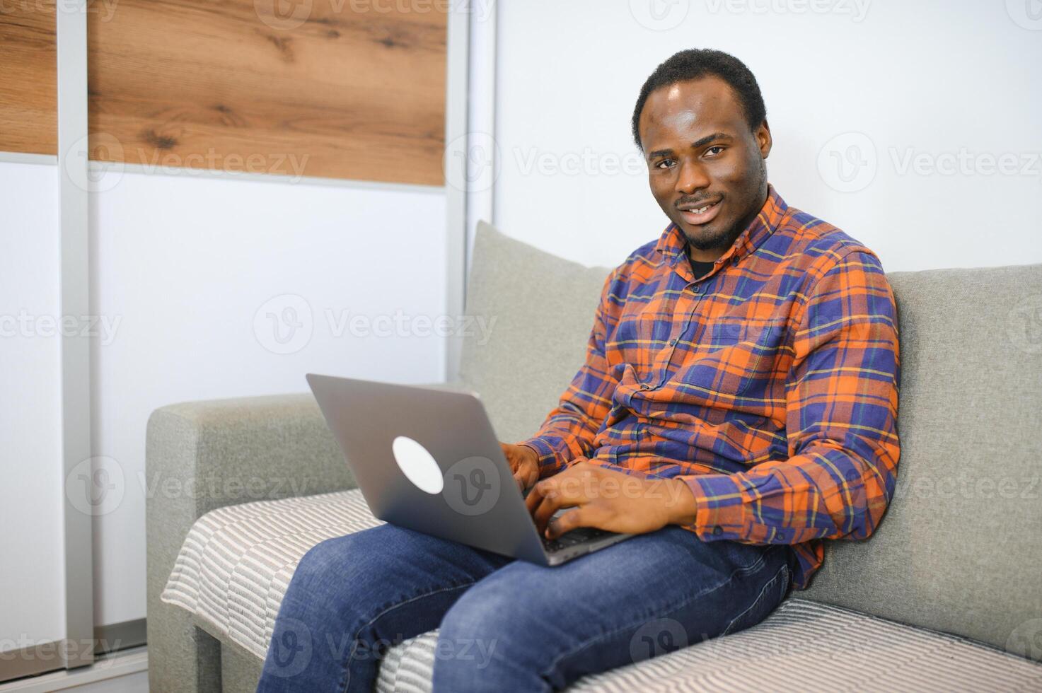 Connecting with an online world. Shot of a happy young man using a laptop while relaxing at home photo