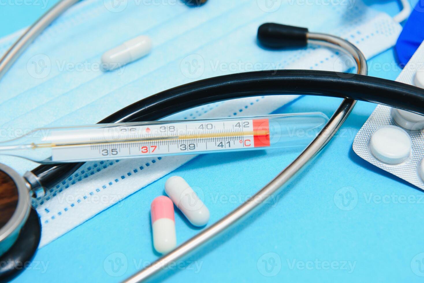 Scattered white pills on blue table.Medical, pharmacy and healthcare concept. Blue background white pills with a medical statoscope, top view photo