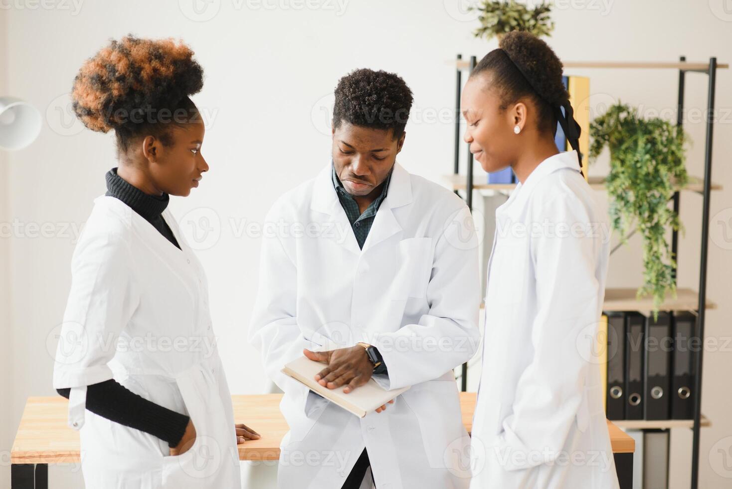 General practitioner and doctor and nurse as african american medical team at hospital. photo
