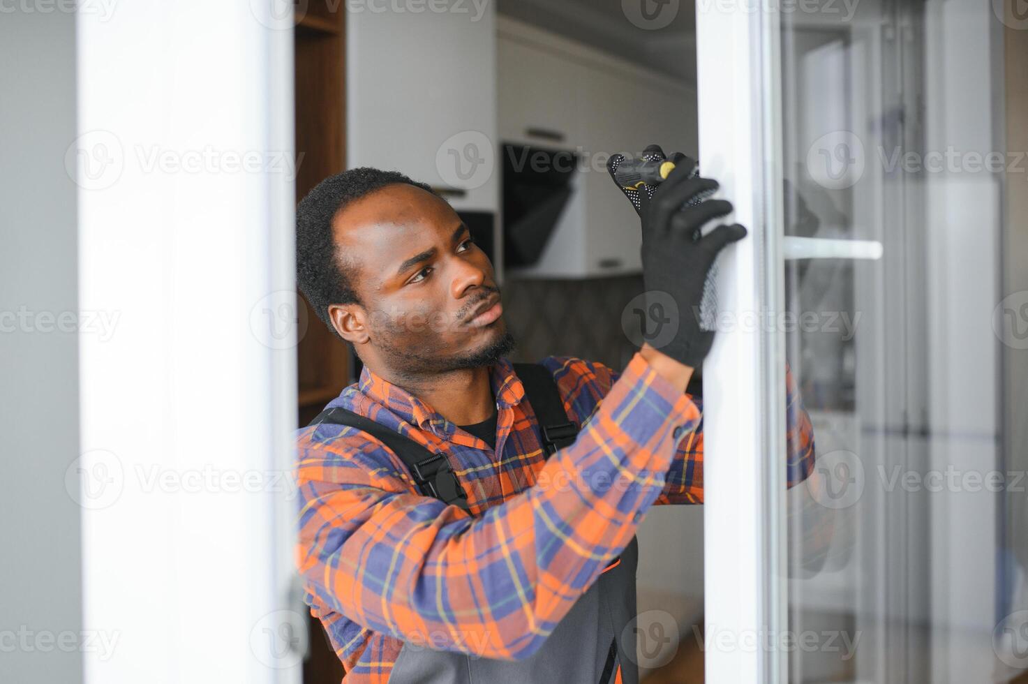 Workman in overalls installing or adjusting plastic windows in the living room at home photo