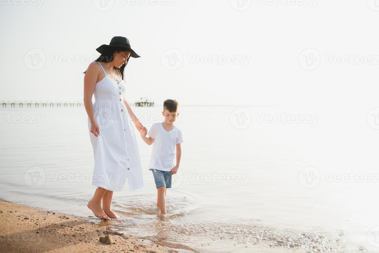 Mother and son playing on the beach at the day time. Concept of friendly family. photo