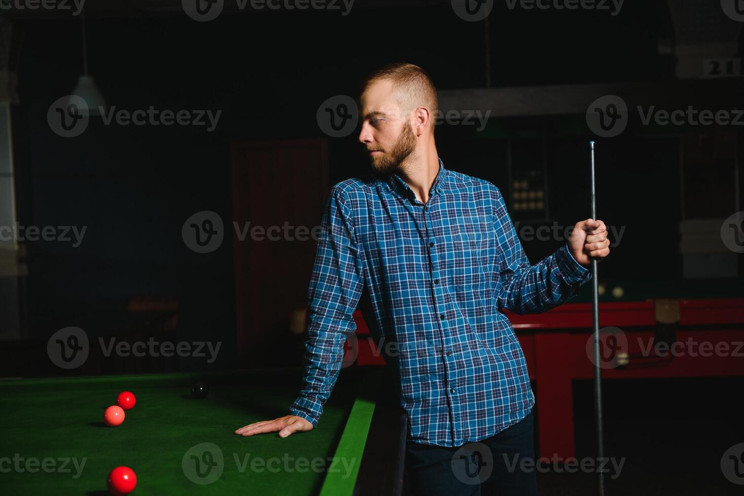 Young handsome man leaning over the table while playing snooker photo