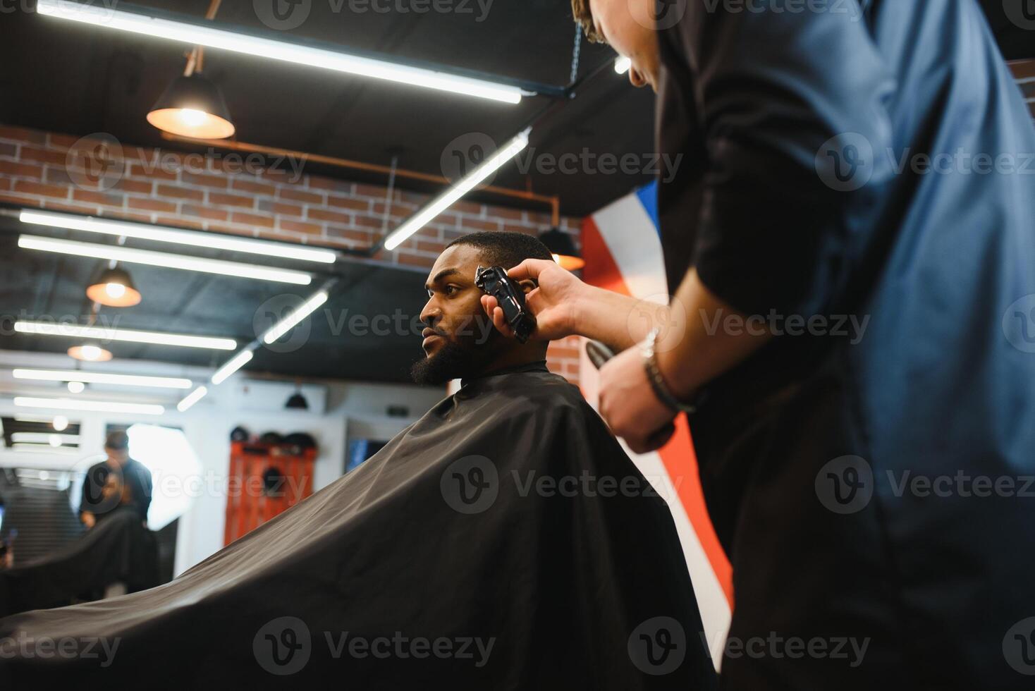 African male client getting haircut at barber shop from professional hairstylist. photo