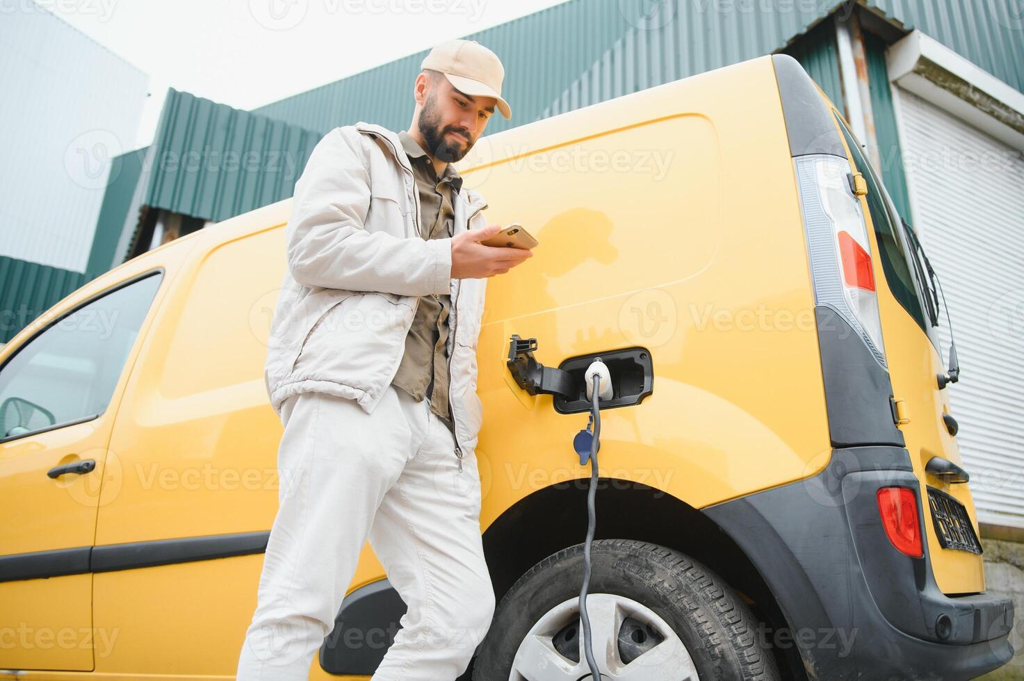 Happy young adult man charging automobile battery from small public station. photo