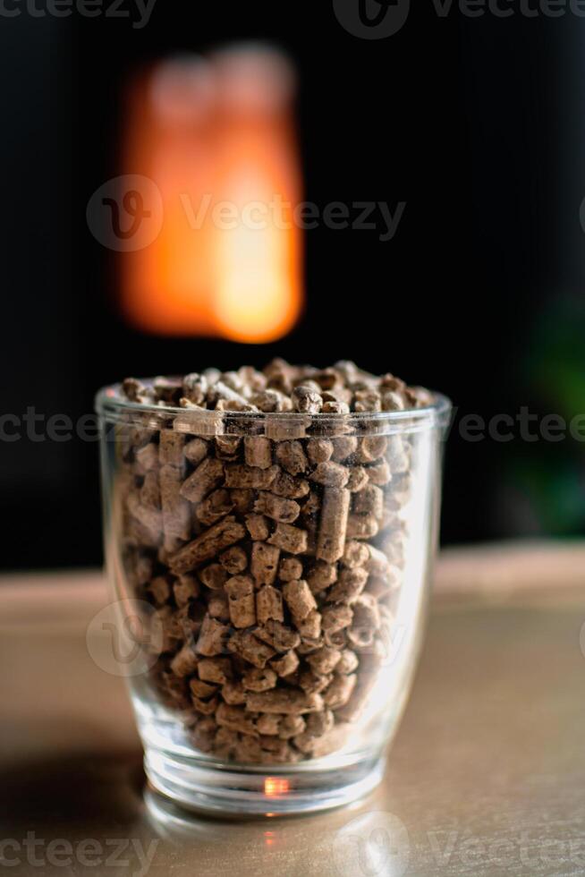 Pellet for stove or boiler in a glass, compressed wood pellet with a stove in background photo