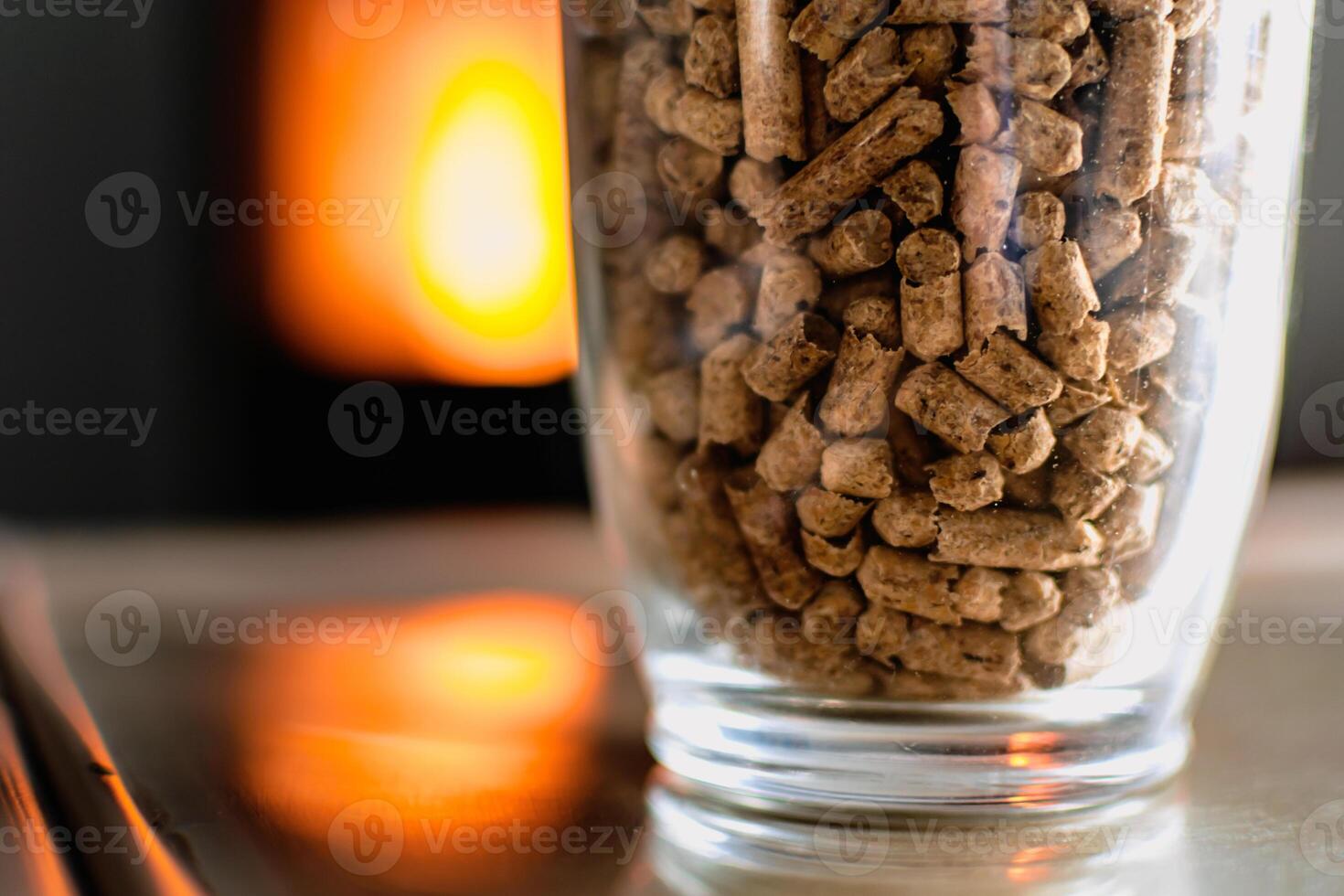 Pellet for stove or boiler in a glass, compressed wood pellet with a stove in background photo