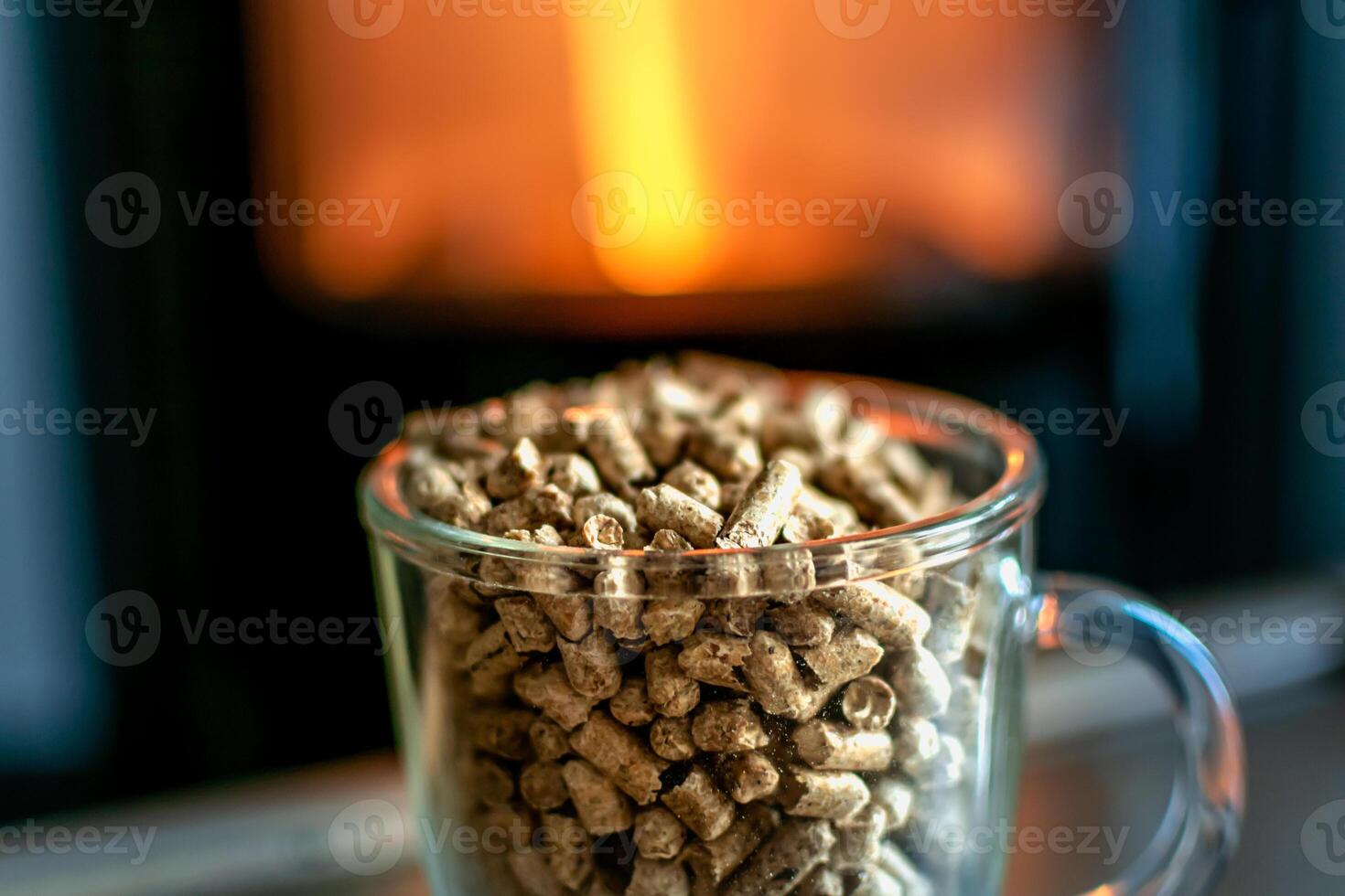 Pellet for stove or boiler in a glass, compressed wood pellet with a stove in background photo