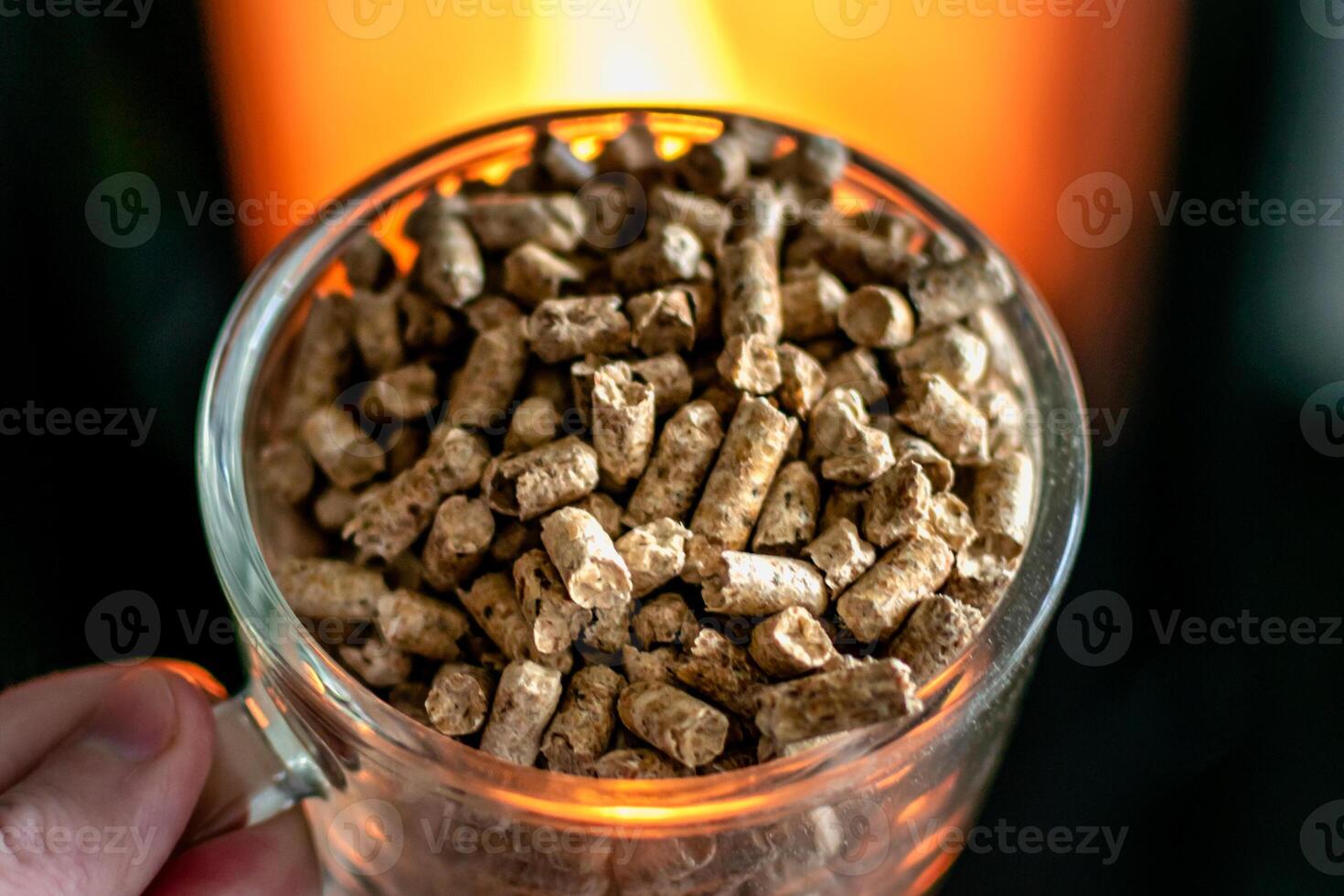 Pellet for stove or boiler in a glass, compressed wood pellet with a stove in background photo