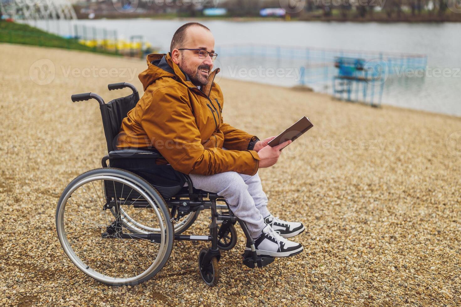 Paraplegic handicapped man in wheelchair is reading book outdoor. photo