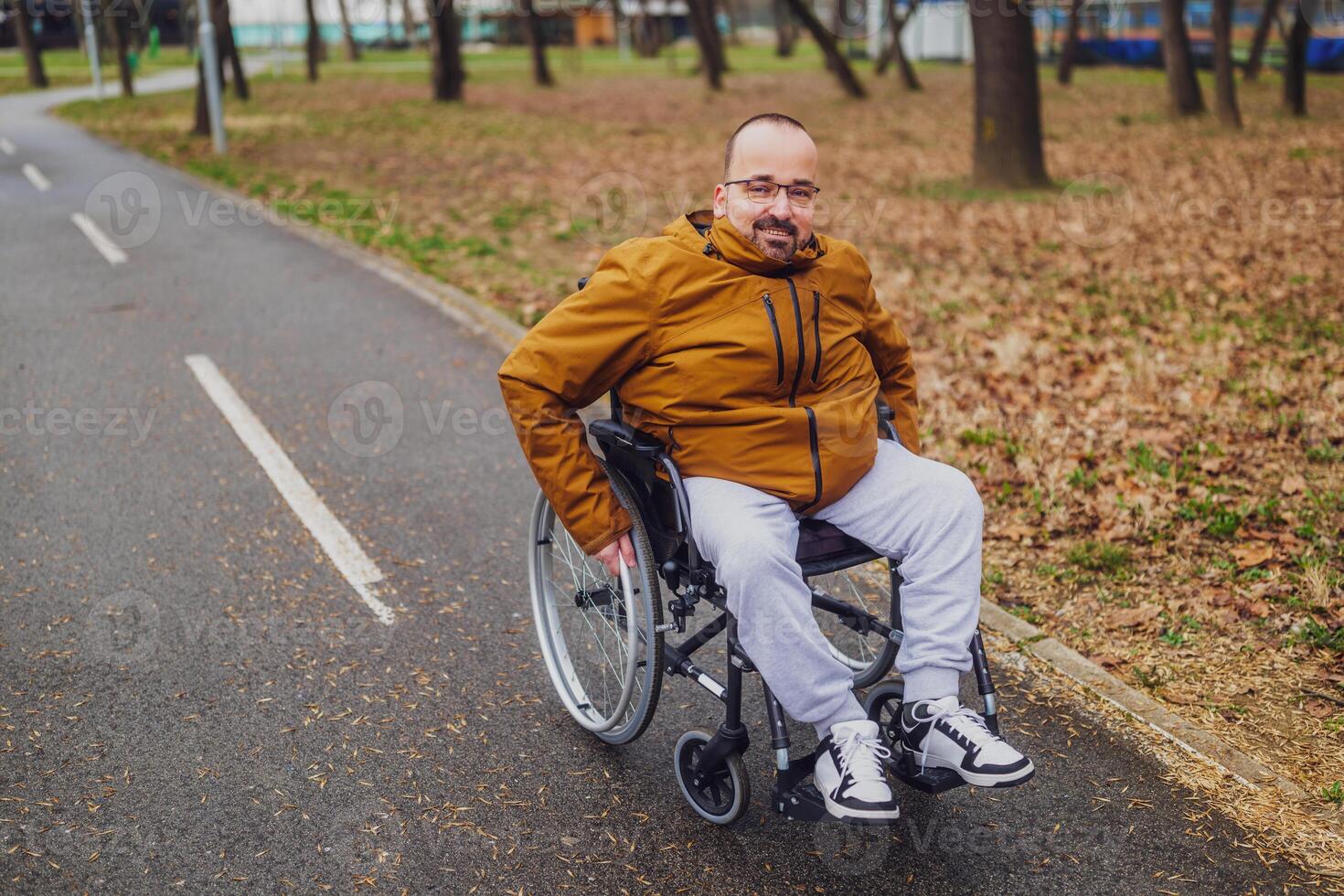 retrato de contento parapléjico minusválido hombre en silla de ruedas en parque. él es laminación en ruta. foto