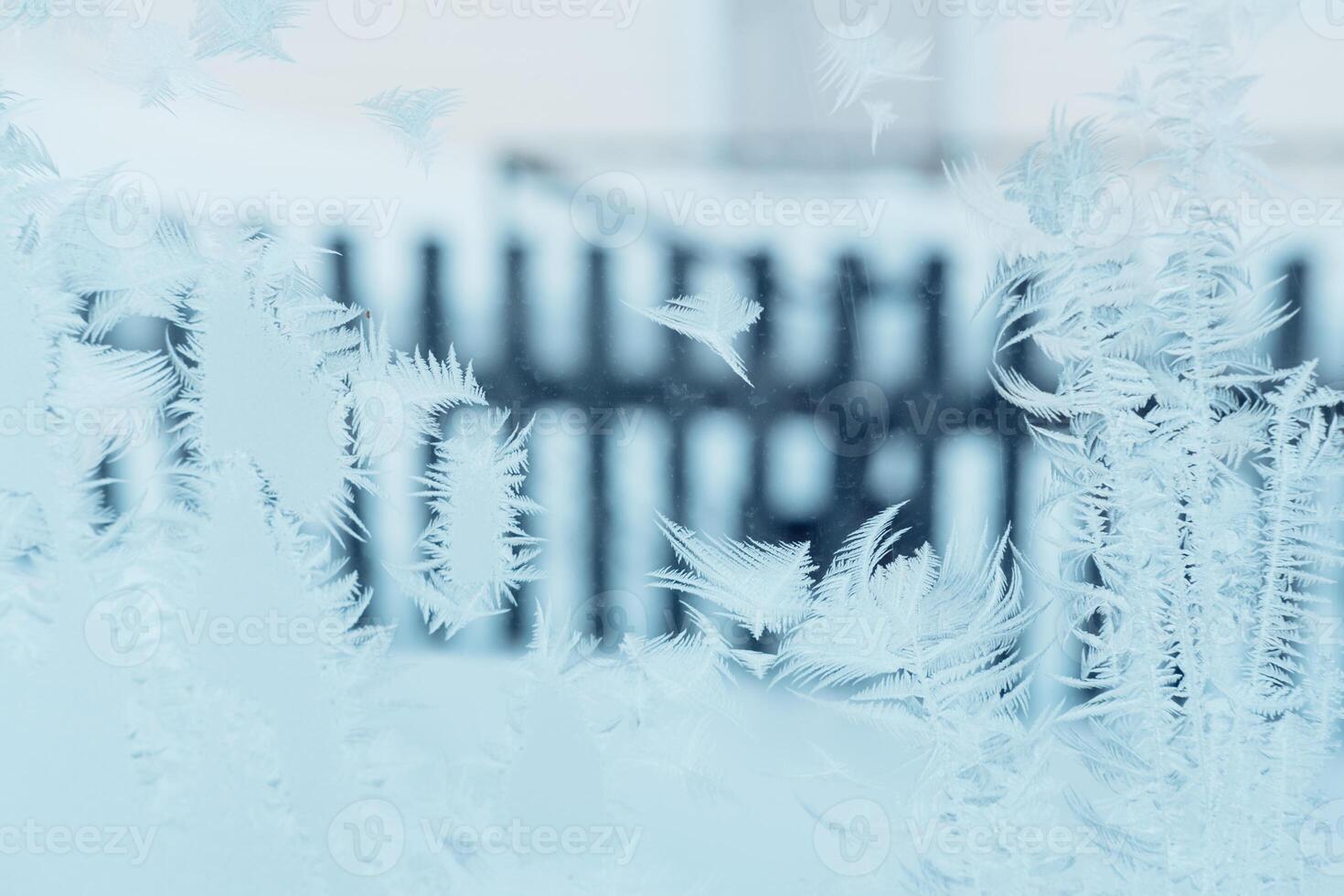 Beautiful frosty patterns on a blue window against the background of a fence photo