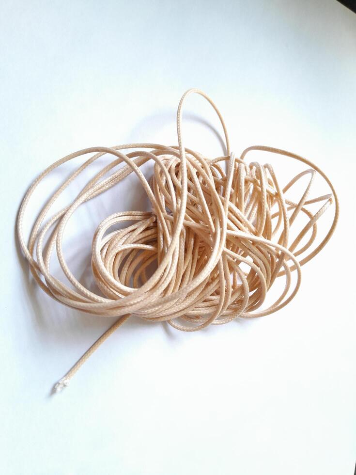 Close up photo of a small brown rope on a white background