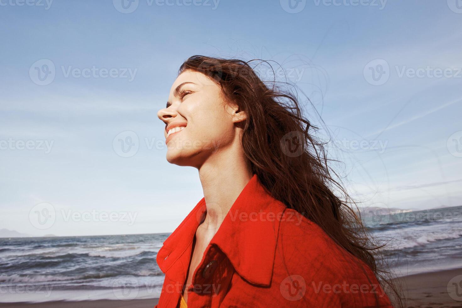 Joyful Woman Embracing Freedom on Sunny Beach, Wearing Red Clothes photo