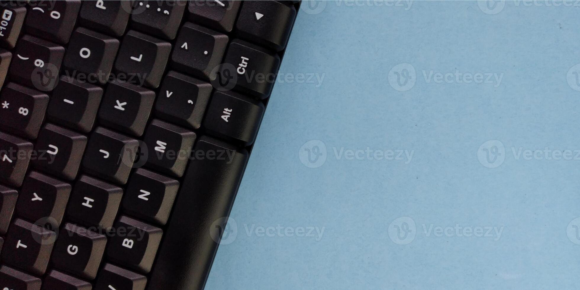 Close up of a black computer keyboard on a blue background with copy space photo