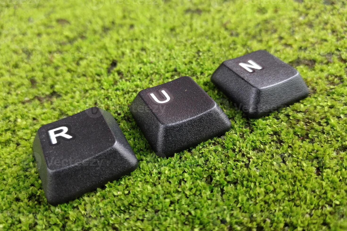 Word RUN made of black plastic letters on green moss background. photo