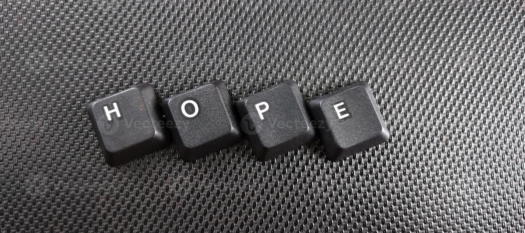 The word hope written with black computer keys on a black background. photo