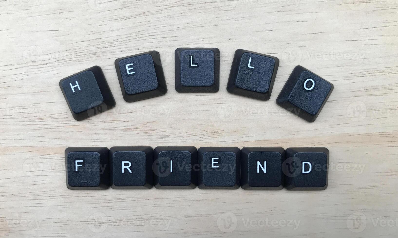 Black keyboard with word Hello Friend on wooden background. Top view. photo