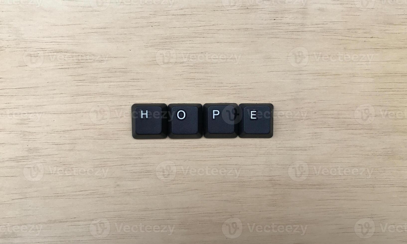 The word HOPE written with black computer keys on wooden background. photo