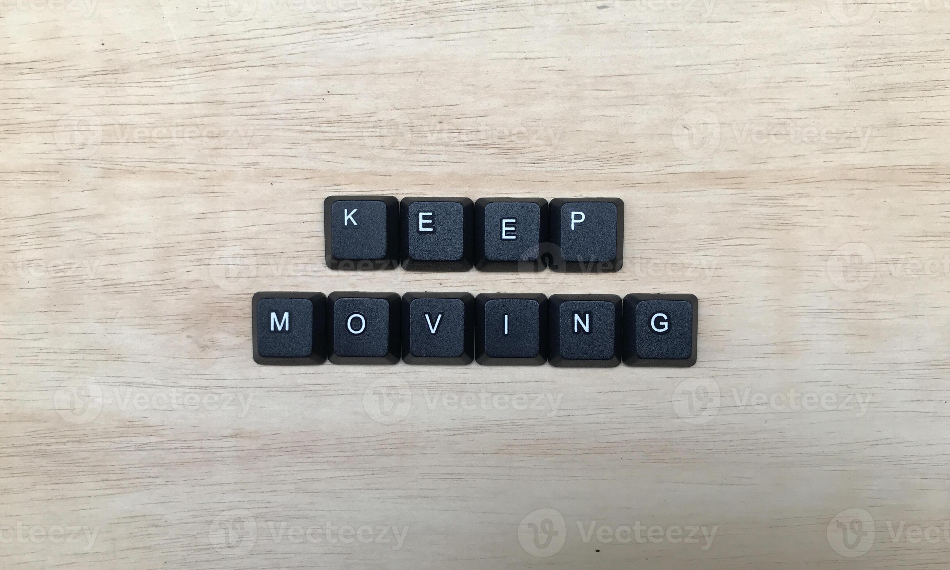 Keep moving word made from black letter buttons on wooden background