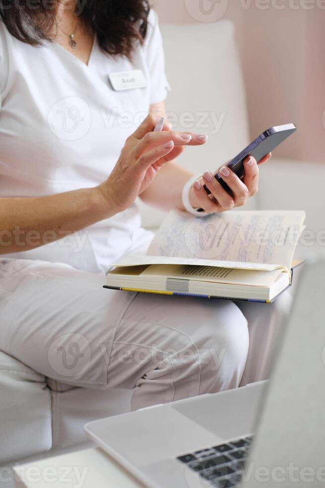 Medical Professional Using Smartphone with Notebook and Laptop photo