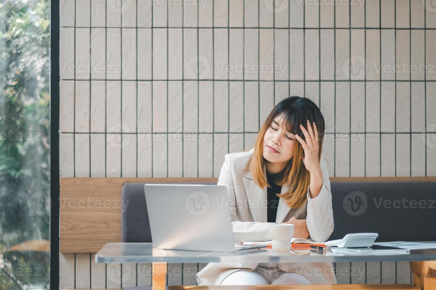 Stressed businesswoman at a cafe with laptop, showing signs of fatigue or headache during a busy workday. photo