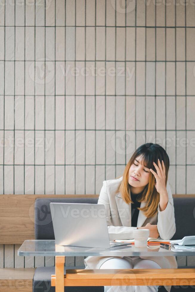 Stressed businesswoman at a cafe with laptop, showing signs of fatigue or headache during a busy workday. photo