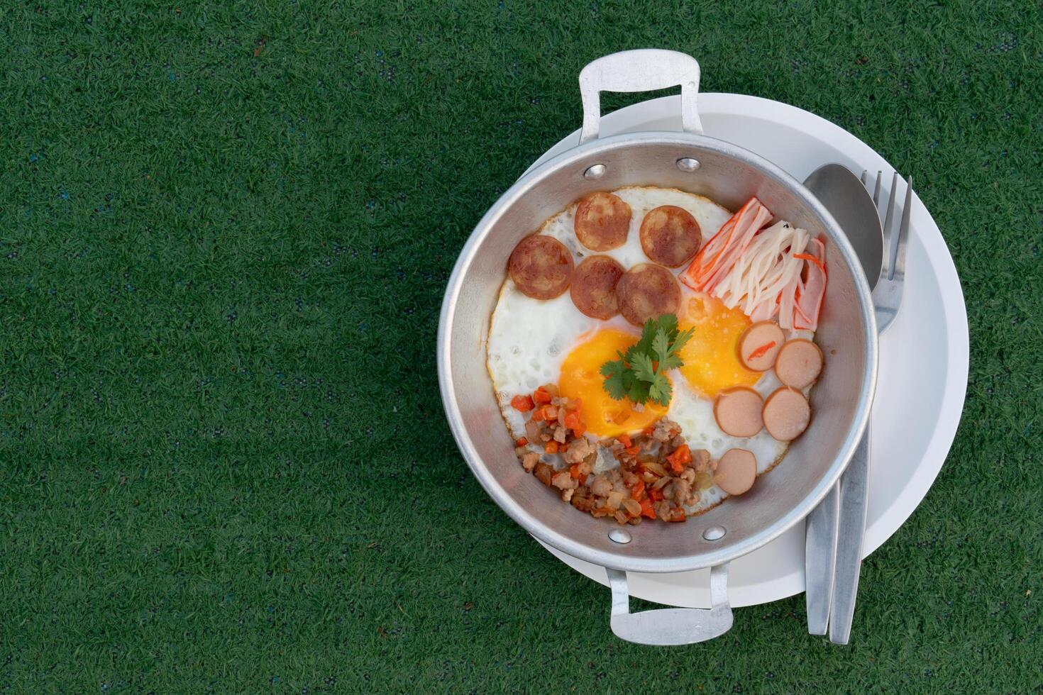 Pan Fried Eggs Topped with minced pork, hot flowers, Chinese sausage and crab sticks. Served in a galvanized plate and placed on a plate.  Placed on artificial grass photo