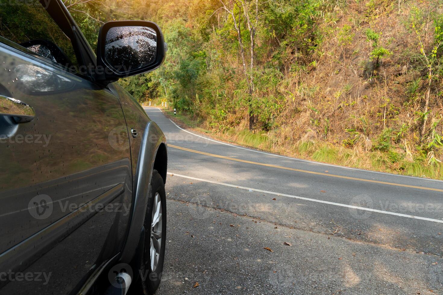 Car parking beside on the aspahlt road. View of beside of fron car.Road around a curve with spring trees. Characteristics of cars parked to rest or wait for something. photo