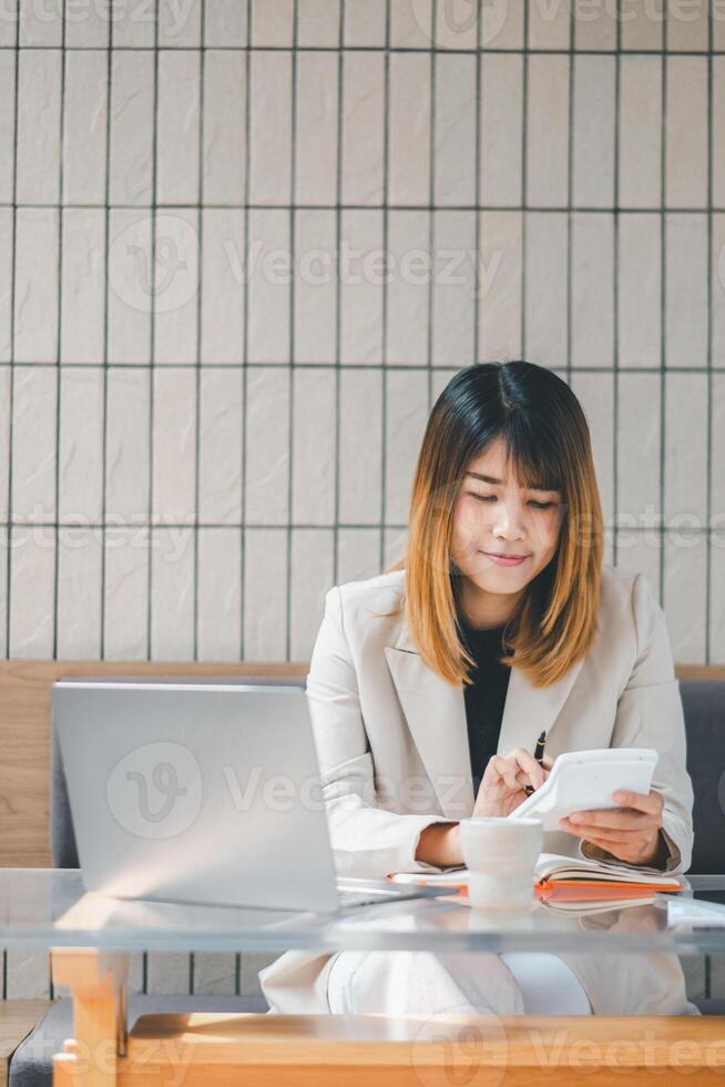 Smiling businesswoman using calculator and laptop at a sunny cafe, a perfect blend of technology and productivity. photo