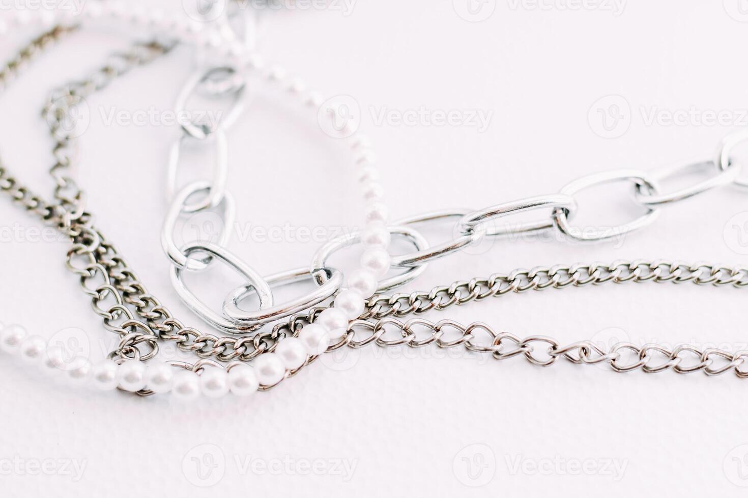 A necklace of white beads with chains of jewelry on a white aesthetic background. photo