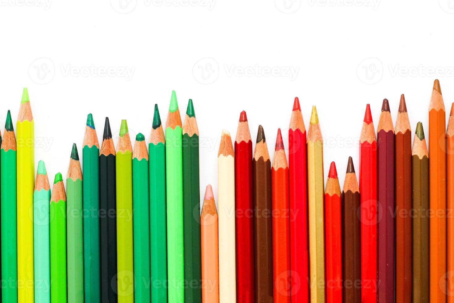 Multi-colored pencils lie on a white table, the green range of colors photo