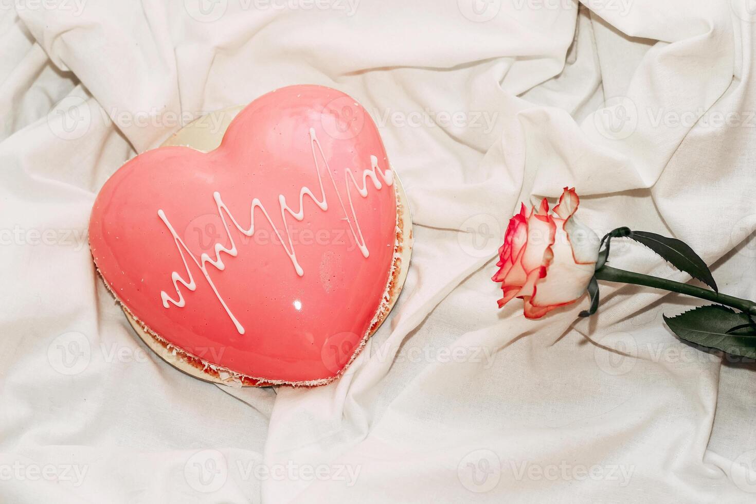 Pink tea rose with heart shaped pink mousse cake. photo
