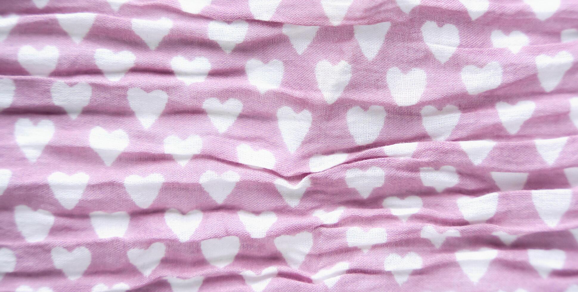 Texture of lilac fabric with with a pattern of white hearts. Abstract background. Close-up. Top view. Selective focus. photo