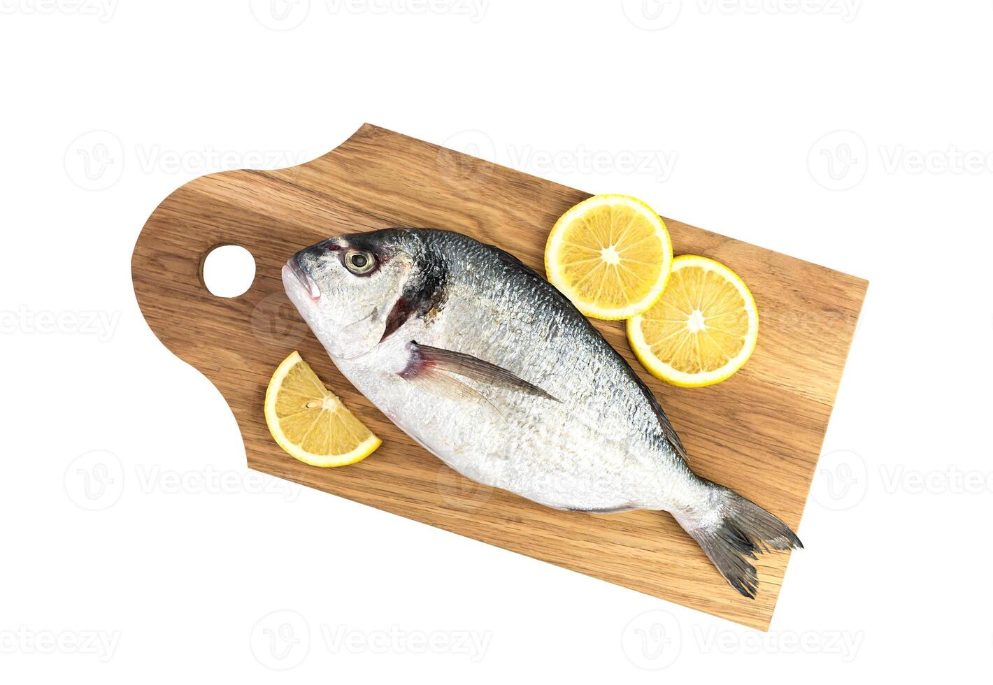Raw fish Dorado with lemon on a wooden board isolated on a white background. Top view. photo