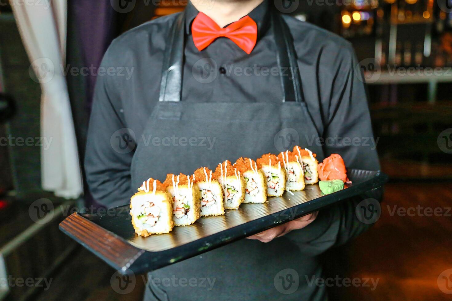 Man in Apron Holding Tray of Sushi photo