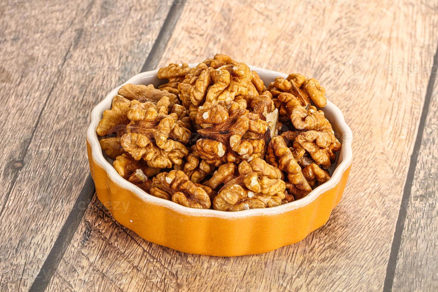 Cracked unshelled walnut in the bowl photo