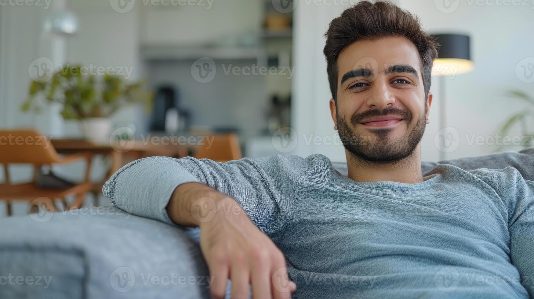 AI Generated Middle Eastern guy sitting on comfortable couch in living room. Cheerful man relaxing on sofa, leaning back, enjoying weekend free time or break from work. photo