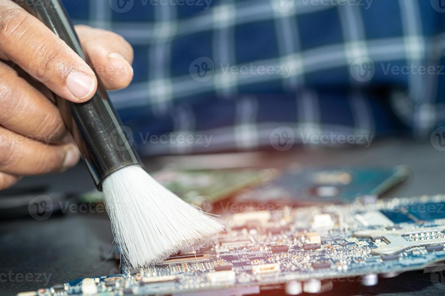 Asian technician repair and cleaning dirty micro circuit main board of smartphone electronic technology with brush, hardware, mobile phone, upgrade concept. photo