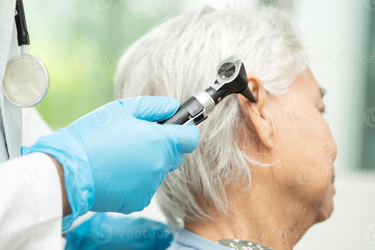 Audiologist or ENT doctor use otoscope checking ear of asian senior woman patient treating hearing loss problem. photo