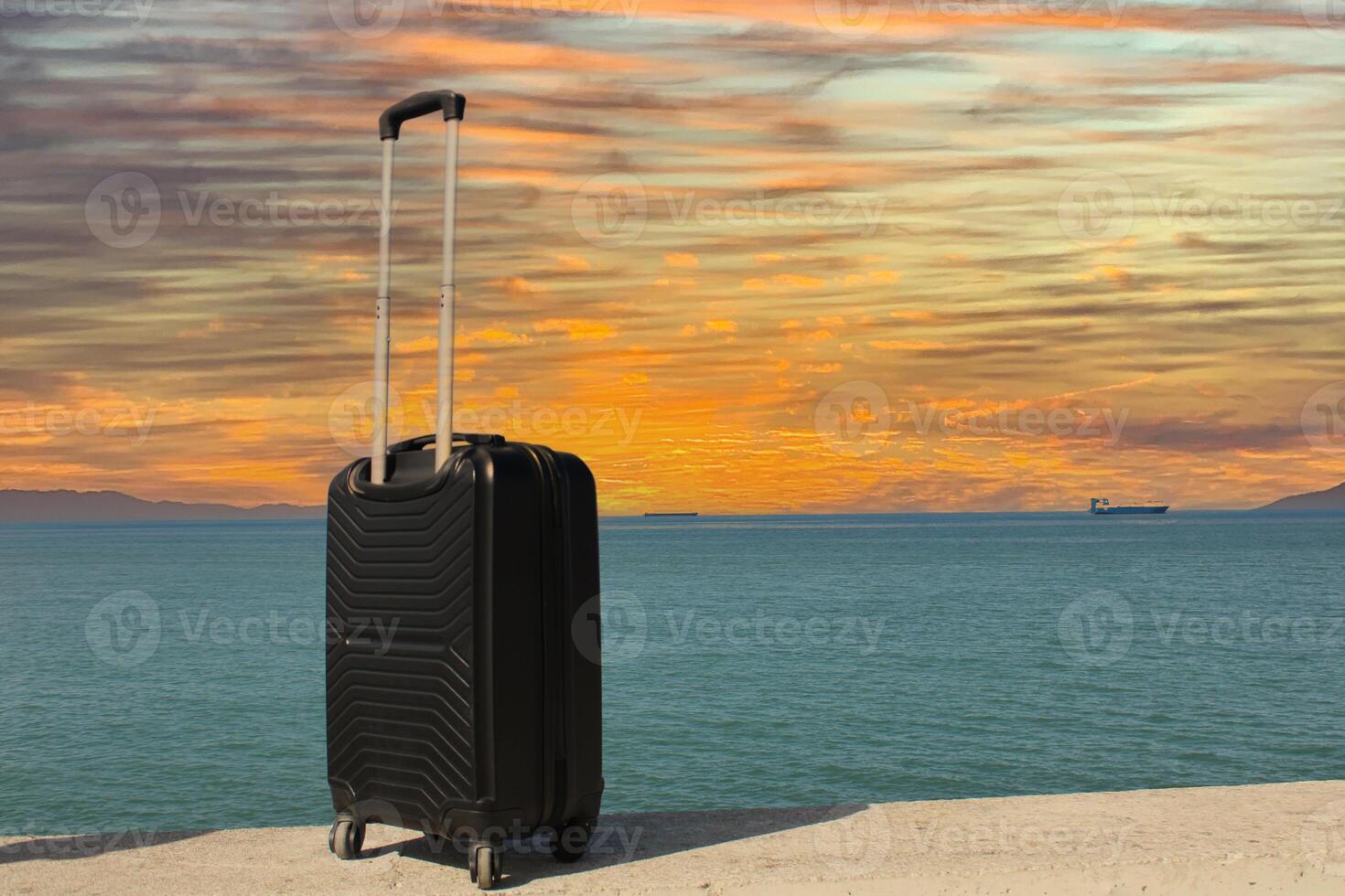 A suitcase is standing on a beach with a sunset in the background. Travel, holiday and vacation consept. Summer time. photo