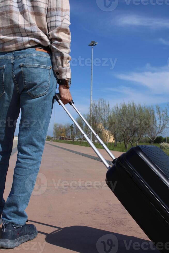 A man pulling a suitcase with a blue sky in the background. Holiday Conspet. Summer Time photo
