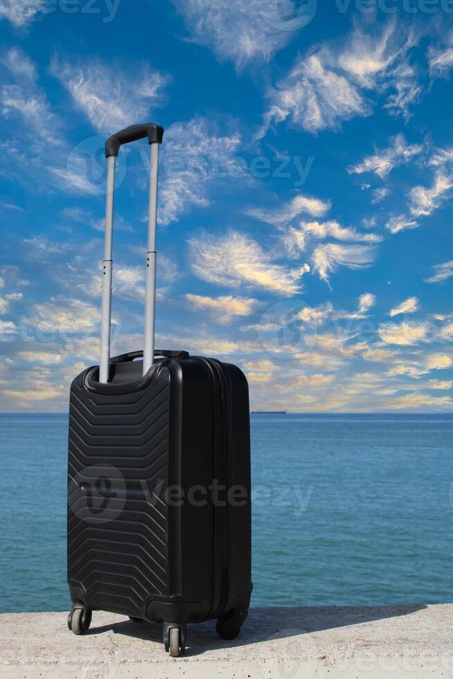 A suitcase is standing on a beach with a sunset in the background. Travel, holiday and vacation consept. Summer time. photo