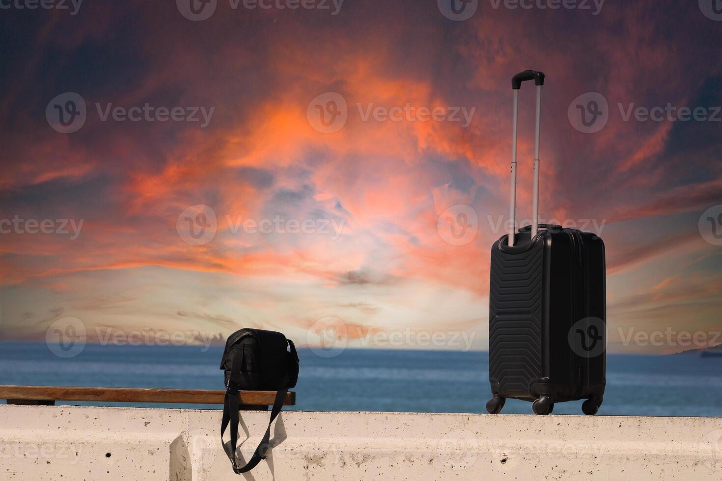 Suitcase and bag are standing on a beach with a sunset in the background.Travel and holiday concept photo