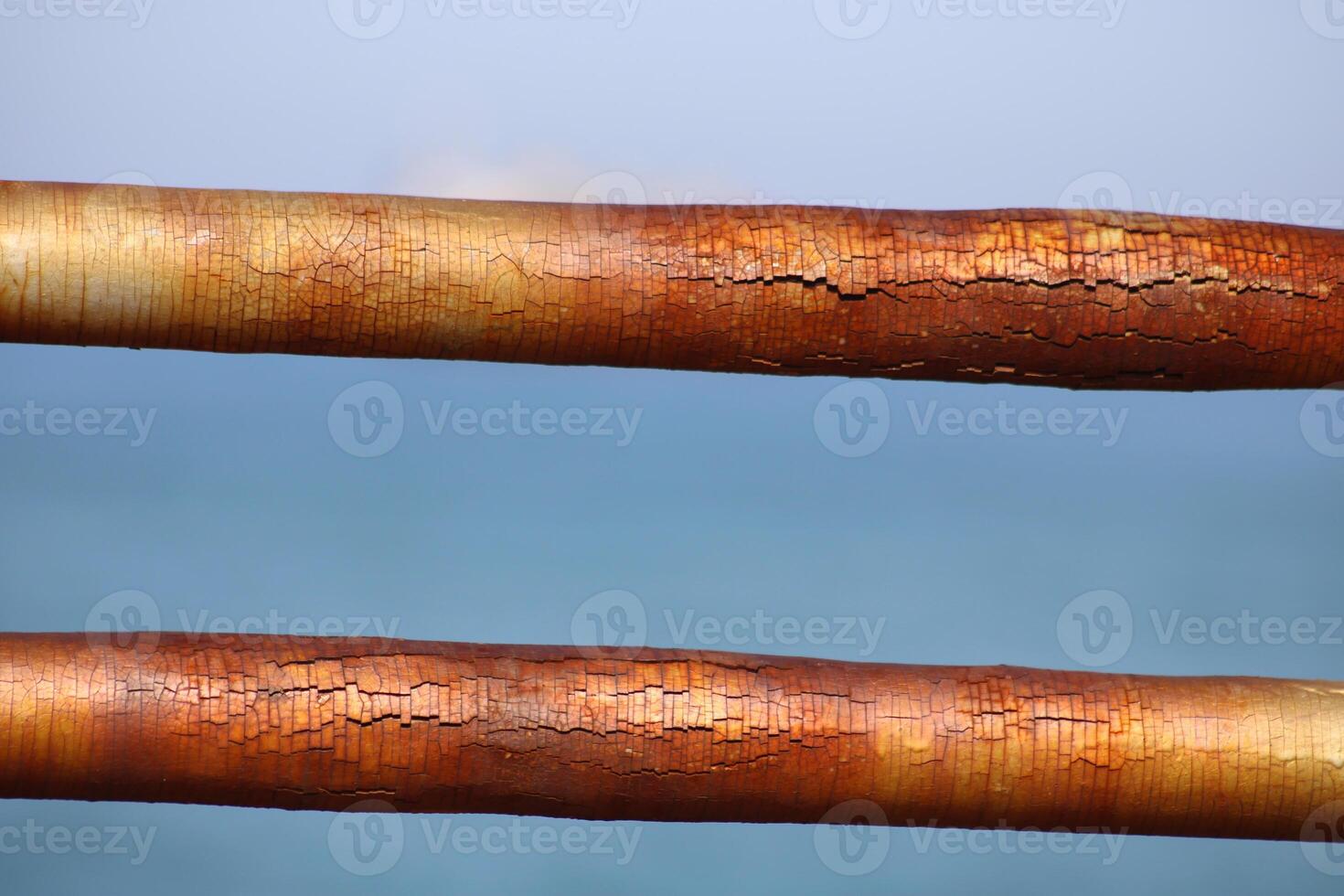 A rusty fence with a blue sea in the background.Rusty iron railing, beautiful sea and sky landscape view between rusty railing gap. photo