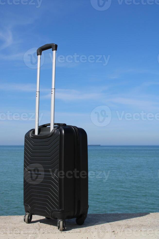 A suitcase is standing on a beach with a sunset in the background. Travel, holiday and vacation consept. Summer time. photo