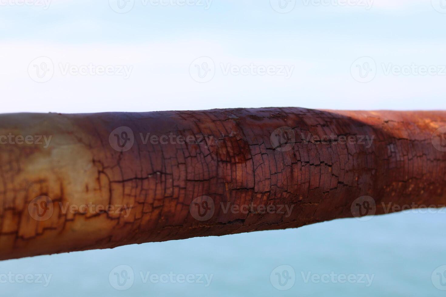 A rusty fence with a blue sea in the background.Rusty iron railing, beautiful sea and sky landscape view between rusty railing gap. photo