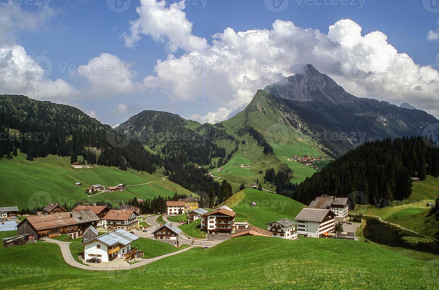 un pueblo en el montañas con verde césped y montañas foto