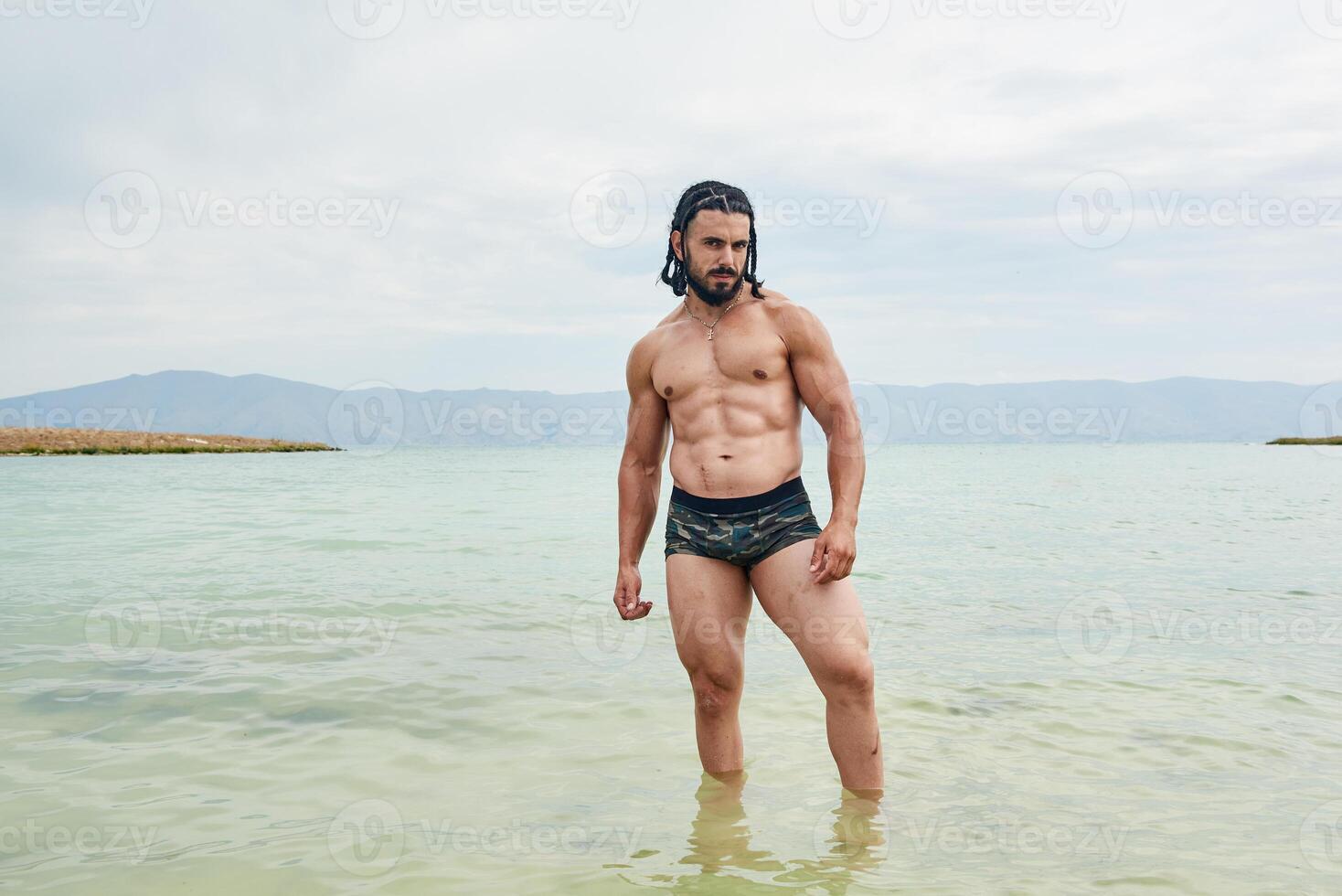 joven muscular hombre hacer ejercicio en el playa, joven muscular hombre haciendo culturismo ejercicios en el playa, atlético joven hombre en el playa foto